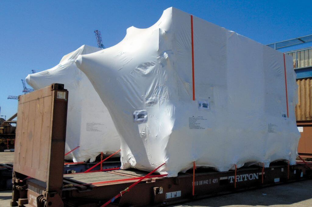 Heavy machinery wrapped in plastic packaging being transported
