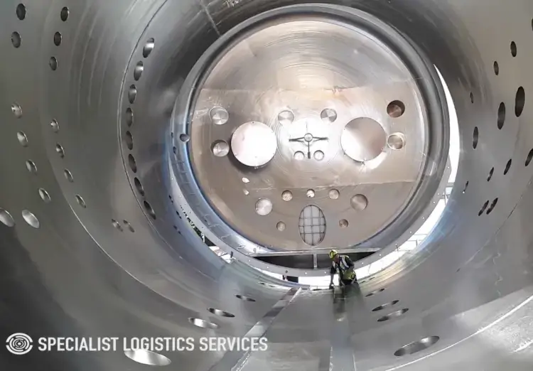 A worker inspecitng the inside of a Satellite Test Chamber.