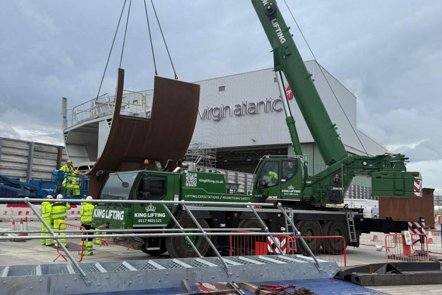 Crane lifting curved steel structure in a loading yard