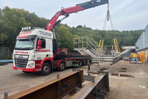 Red crane loading equipment onto a flatbed trailer